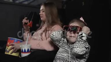 妈妈带着女儿在电影院的椅子上戴着3d眼镜。